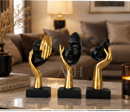Set of 3 abstract black and gold face sculptures on a marble coffee table