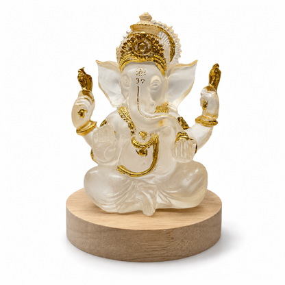 Translucent Ganesha idol with gold accents on natural wood stand – front view