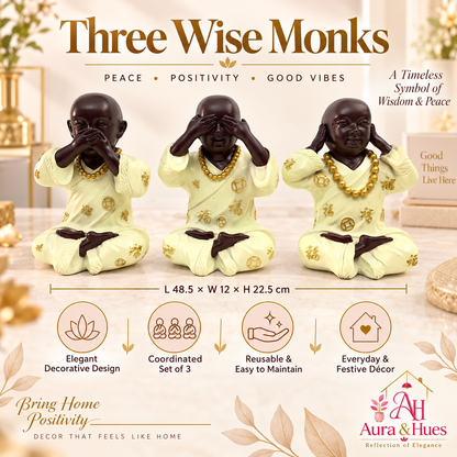 Three meditating monk figurines with cream robes and gold details